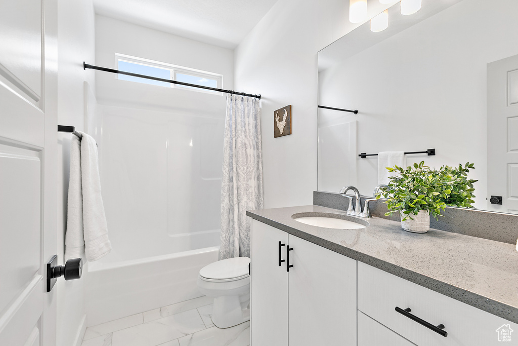 Bathroom with vanity, marble look tile flooring, toilet, and shower / tub combo