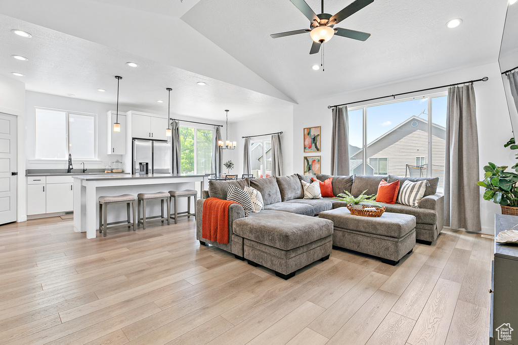 Living room with vaulted ceiling, ceiling fan, light wood-style floors, and recessed lighting
