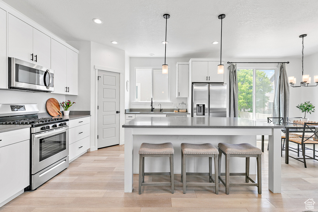 Kitchen with stainless steel appliances, a kitchen breakfast bar, recessed lighting, a sink, and a chandelier