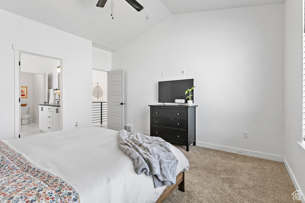 Carpeted bedroom featuring high vaulted ceiling, connected bathroom, baseboards, and ceiling fan