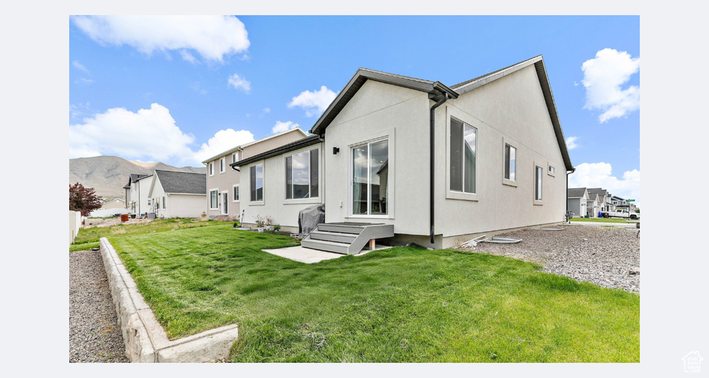 Back of property featuring a lawn and stucco siding