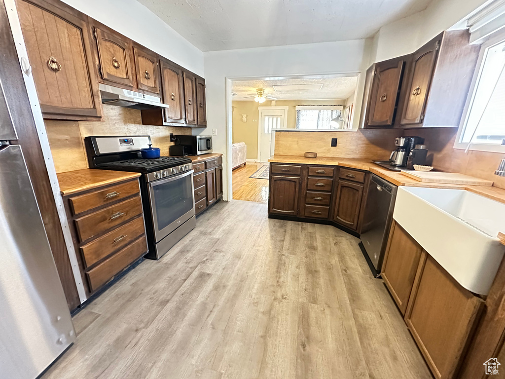 Kitchen featuring stainless steel appliances, under cabinet range hood, light countertops, and healthy amount of natural light