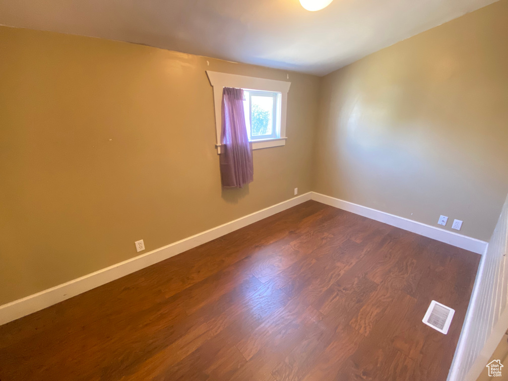 Empty room featuring dark wood finished floors and baseboards