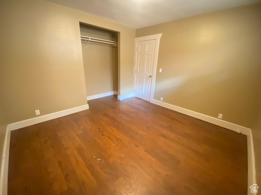 Unfurnished bedroom featuring wood finished floors, baseboards, and a closet