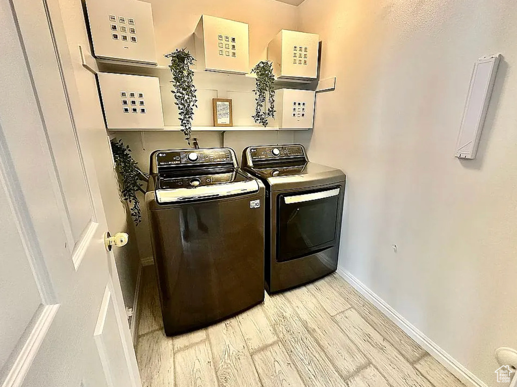 Laundry room with washer and dryer, wood finished floors, and baseboards
