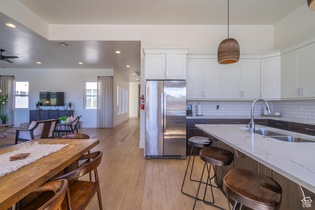 Kitchen with freestanding refrigerator, a sink, light stone countertops, backsplash, and open floor plan
