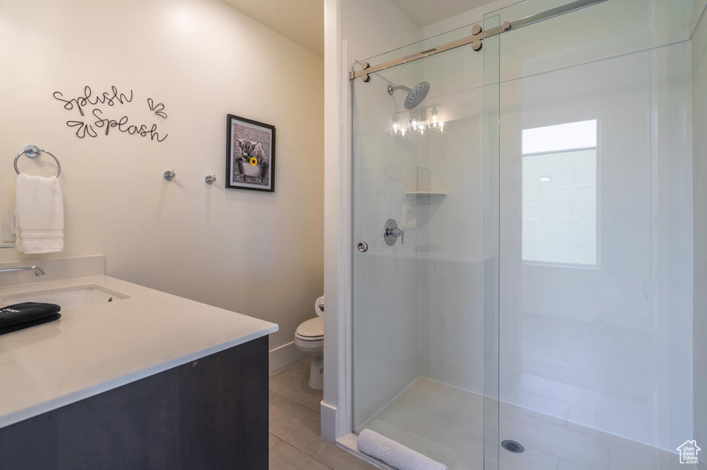 Bathroom featuring a stall shower, toilet, vanity, and tile patterned flooring