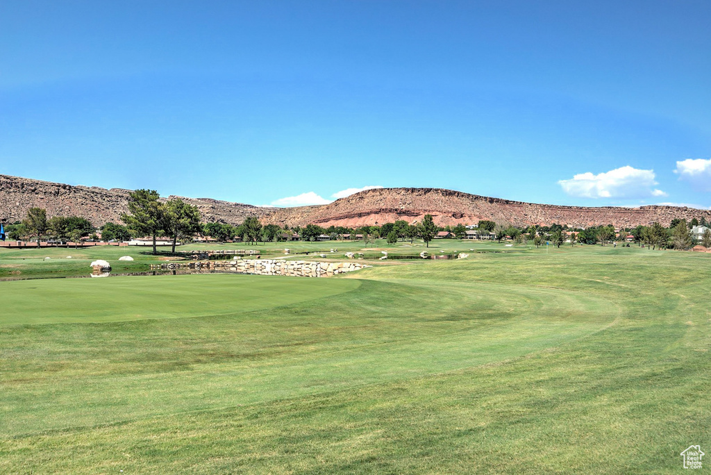View of community with view of golf course, a mountain view, and a yard
