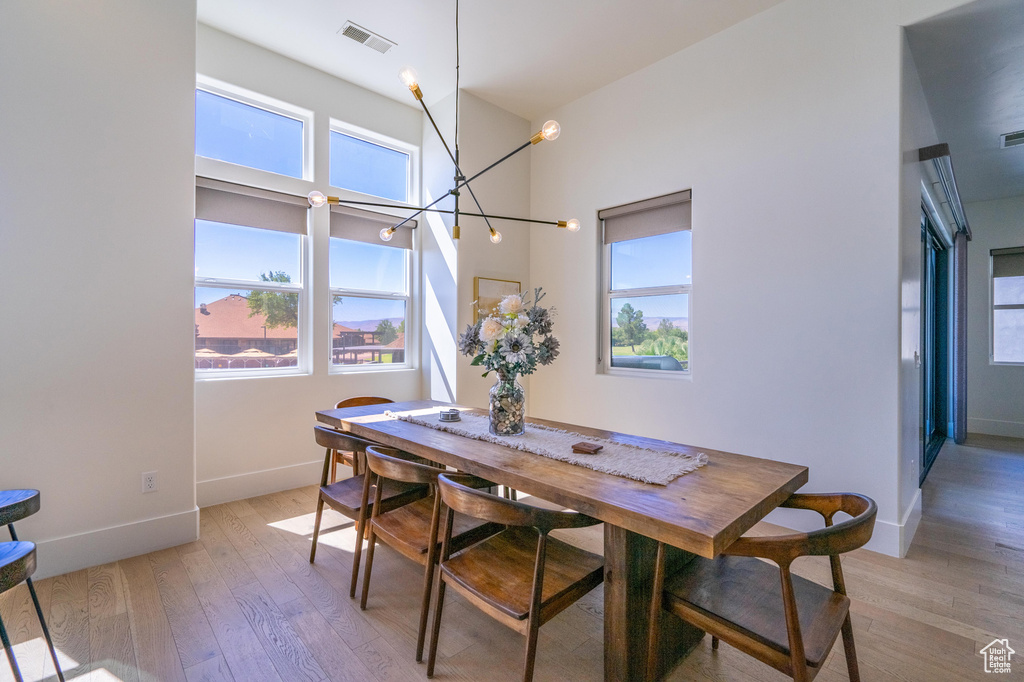 Dining room with plenty of natural light, a chandelier, baseboards, and light wood finished floors