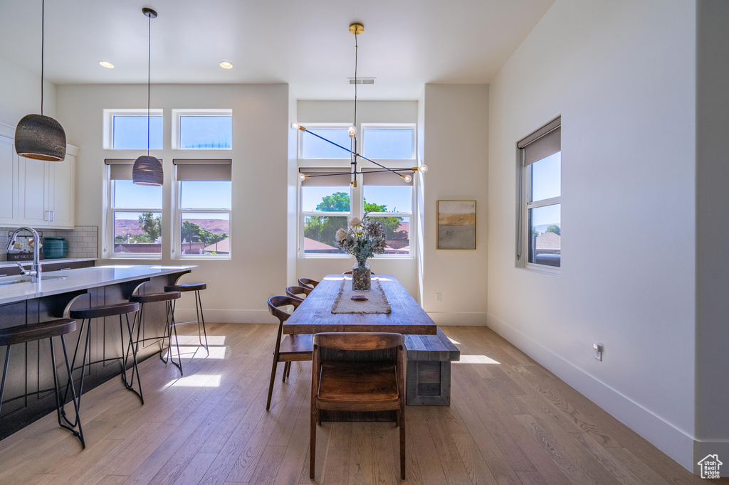 Dining area featuring light wood-style floors, healthy amount of natural light, baseboards, recessed lighting, and a chandelier