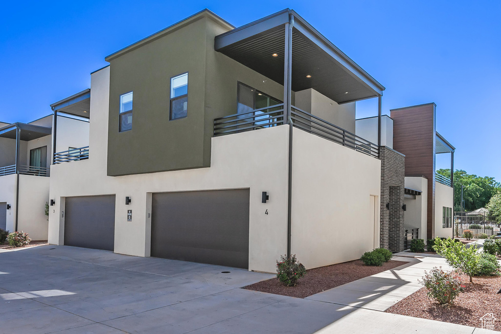 View of front of home featuring a balcony, stucco siding, a garage, and concrete driveway