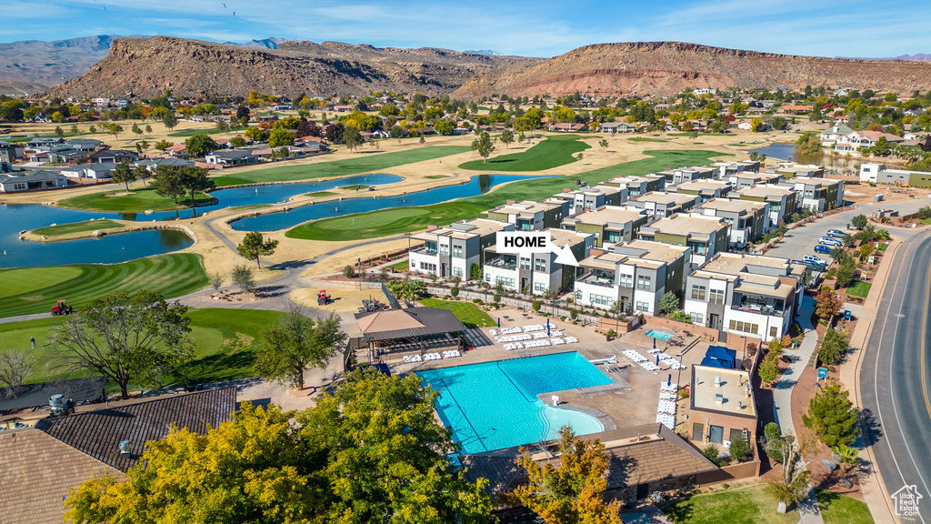 Aerial perspective of suburban area with a golf course, a water and mountain view, and a pool area