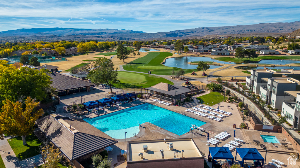 Aerial view of residential area with a pool area, a water and mountain view, and a golf club