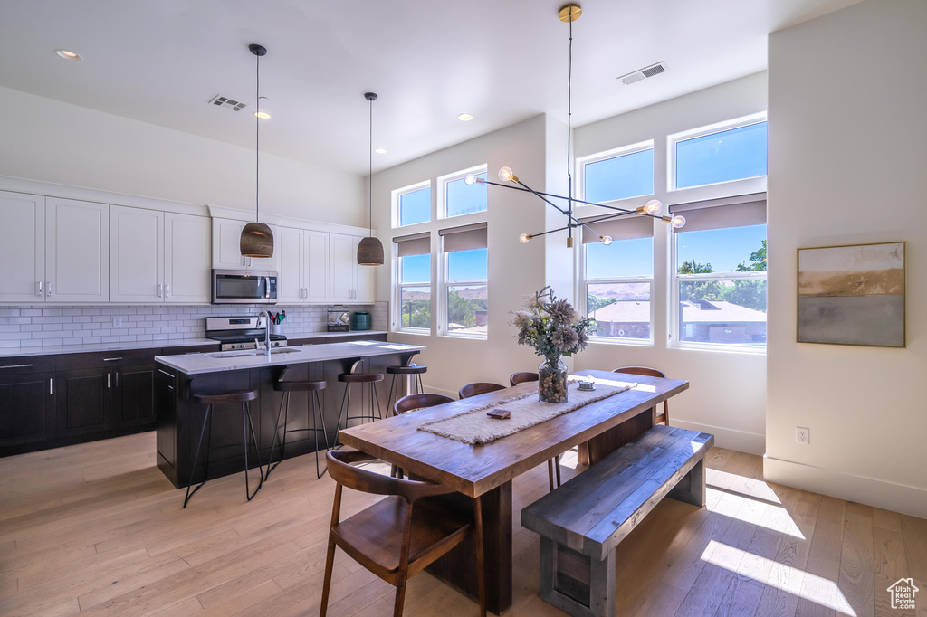 Dining space featuring plenty of natural light, light wood-style floors, a chandelier, and recessed lighting