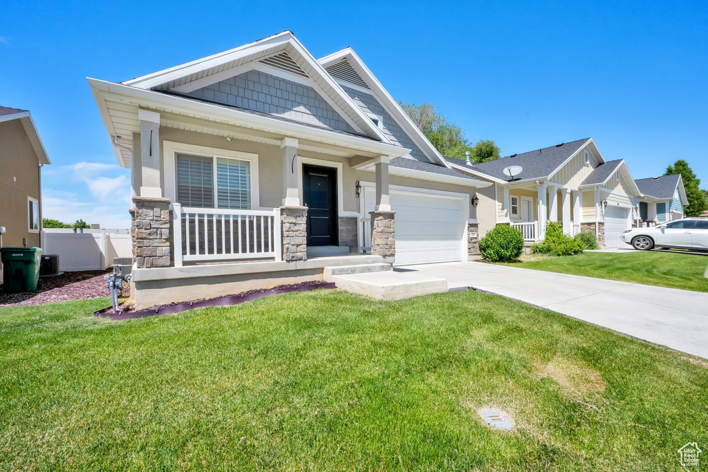 Craftsman house with stone siding, a porch, a garage, and a front yard