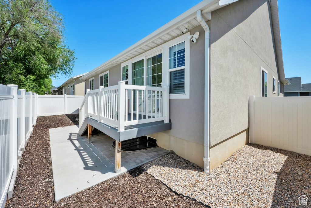 Back of house featuring a fenced backyard, a deck, stucco siding, and a patio