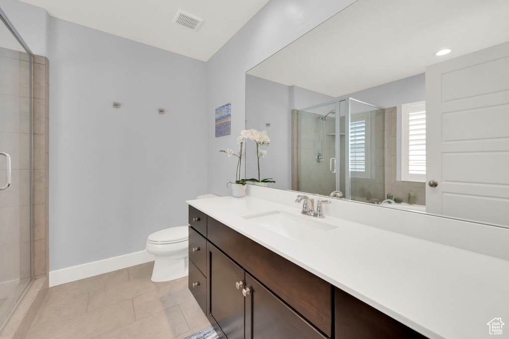Full bathroom featuring vanity, a stall shower, baseboards, toilet, and tile patterned flooring