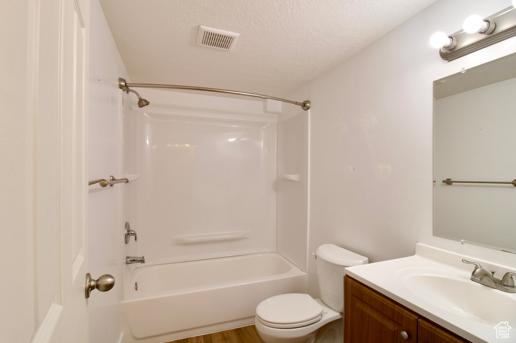 Bathroom featuring vanity, toilet, shower / bath combination, and a textured ceiling