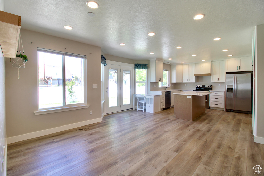 Kitchen featuring stainless steel appliances, a center island, recessed lighting, light countertops, and a sink