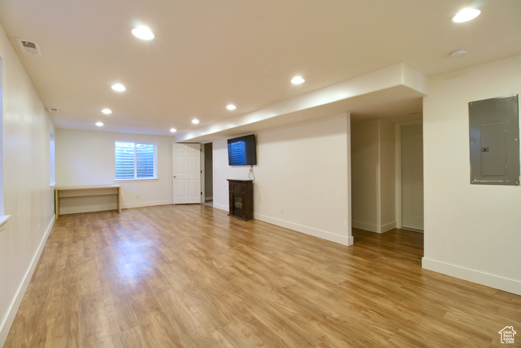 Below grade area featuring electric panel, light wood-type flooring, recessed lighting, and baseboards