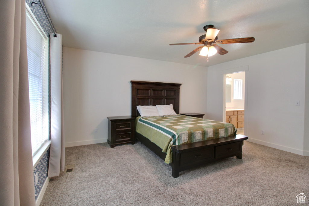 Bedroom with light colored carpet, baseboards, a ceiling fan, and ensuite bathroom