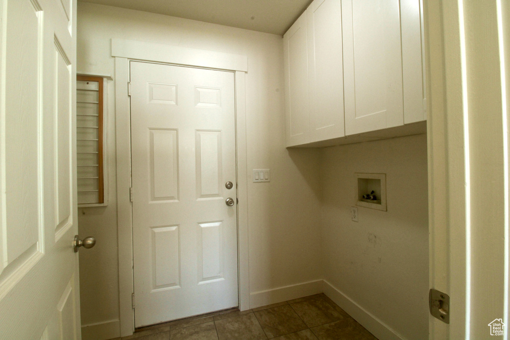 Washroom featuring cabinet space, hookup for a washing machine, baseboards, and tile patterned flooring