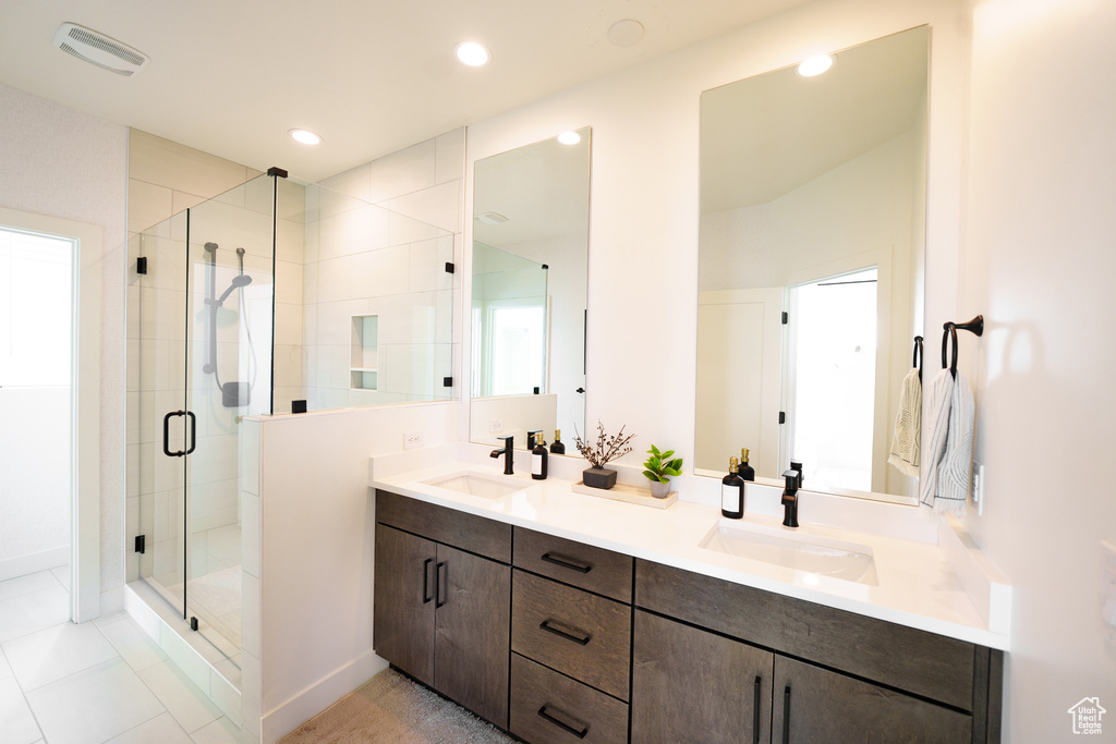 Full bathroom featuring a shower stall, double vanity, recessed lighting, tile patterned floors, and baseboards