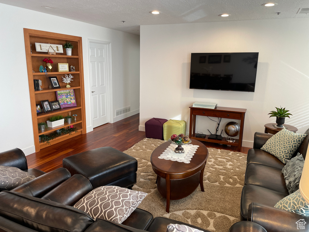 Living area with wood finished floors, baseboards, recessed lighting, and a textured ceiling