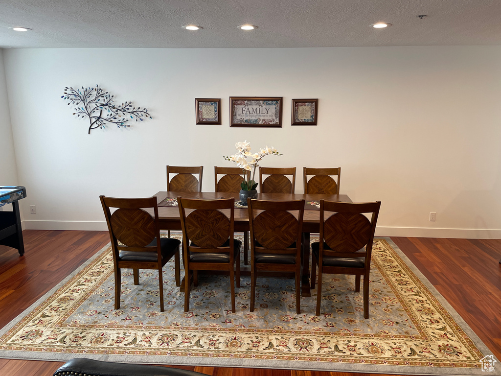 Dining space with wood finished floors, baseboards, a textured ceiling, and recessed lighting
