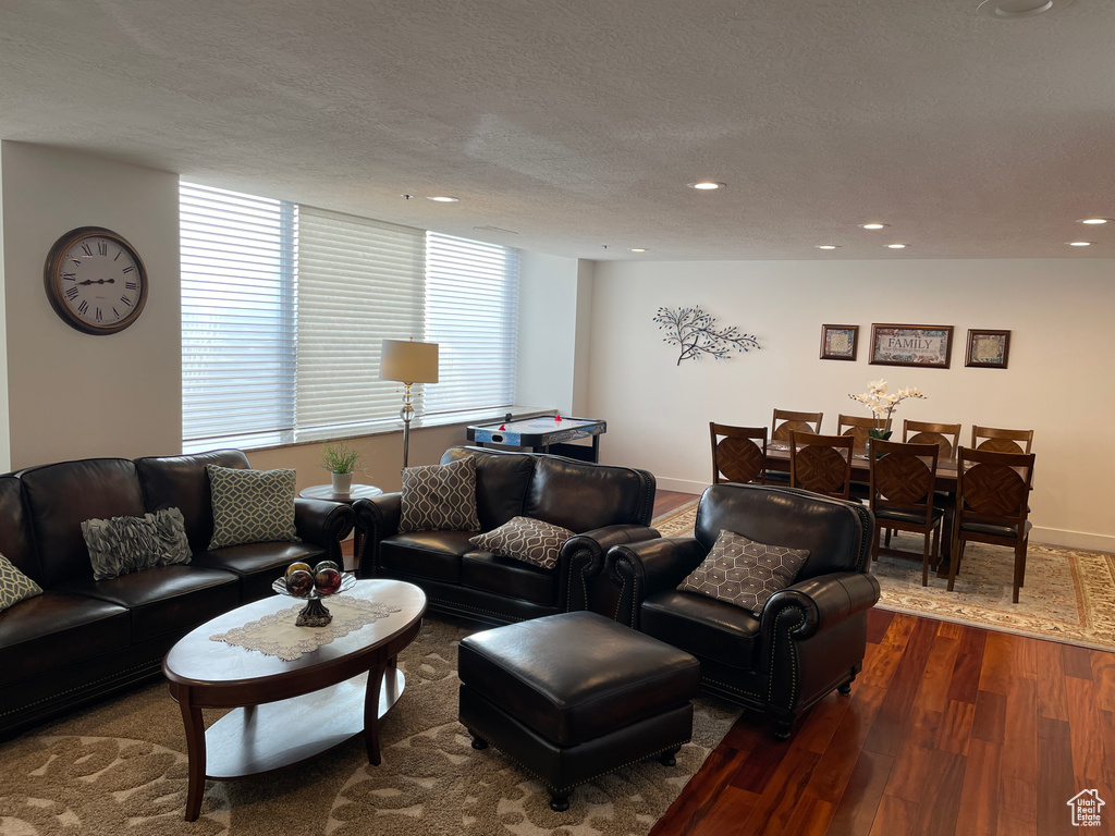 Living room with dark wood finished floors, recessed lighting, a textured ceiling, and baseboards