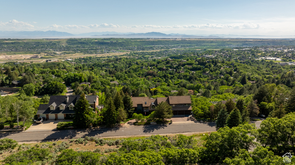 Aerial view of property and surrounding area featuring a mountain backdrop and a forest
