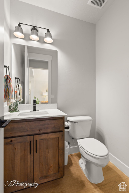 Bathroom with toilet, baseboards, vanity, and wood finished floors