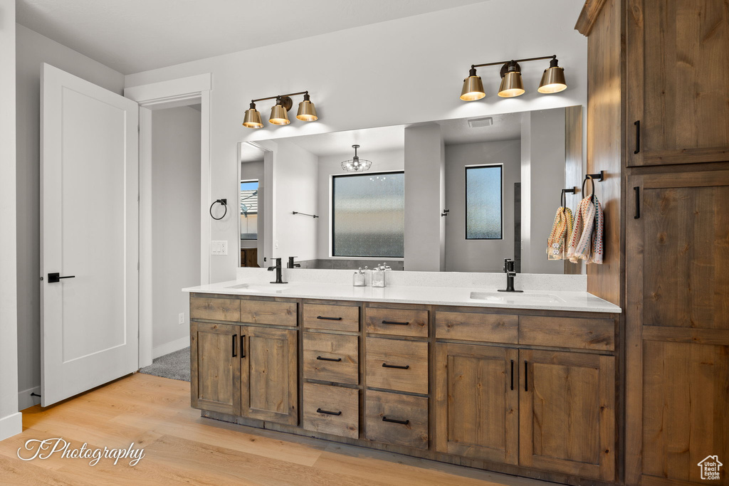 Full bath featuring double vanity, wood finished floors, and baseboards