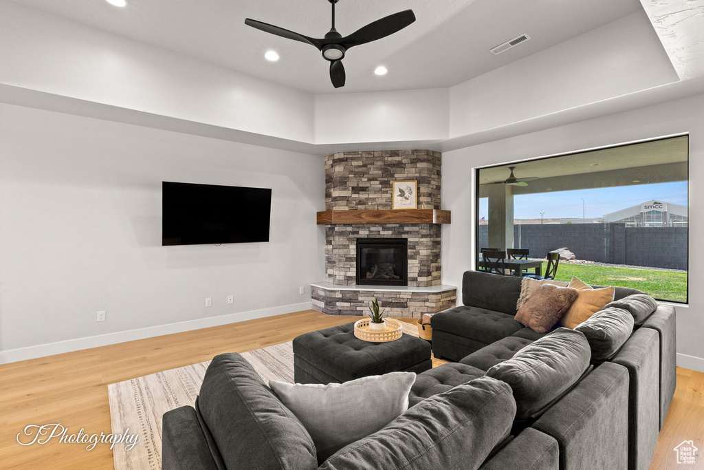 Living room featuring a ceiling fan, light wood-style flooring, a fireplace, recessed lighting, and baseboards