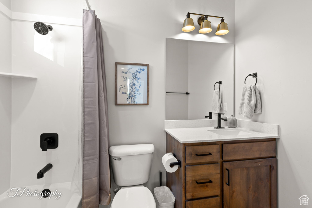 Bathroom with vanity, toilet, and shower / tub combo with curtain
