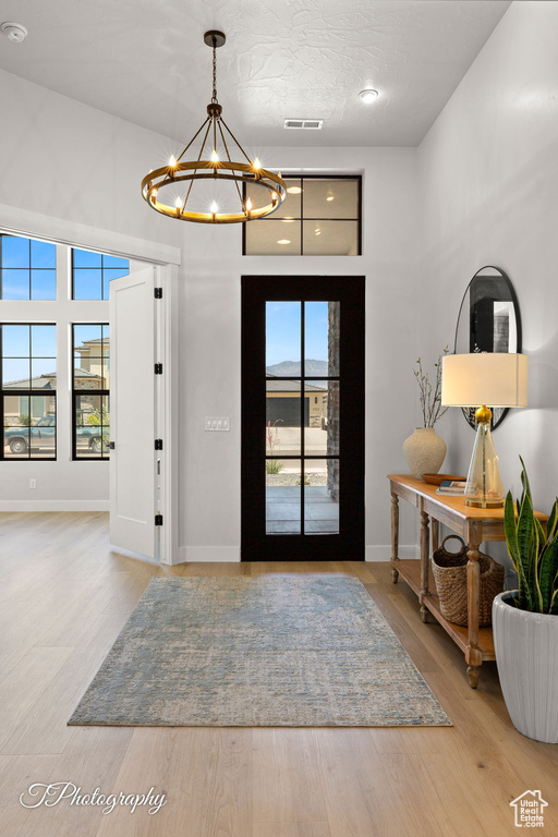 Entryway with a chandelier, wood finished floors, and baseboards