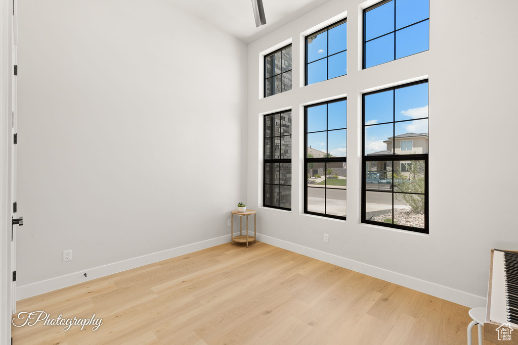 Spare room featuring wood finished floors, baseboards, and a high ceiling