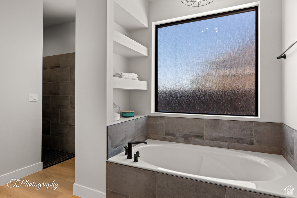 Full bathroom featuring a garden tub and wood finished floors