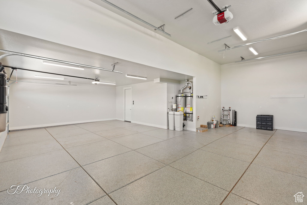 Garage with a garage door opener, water heater, and baseboards