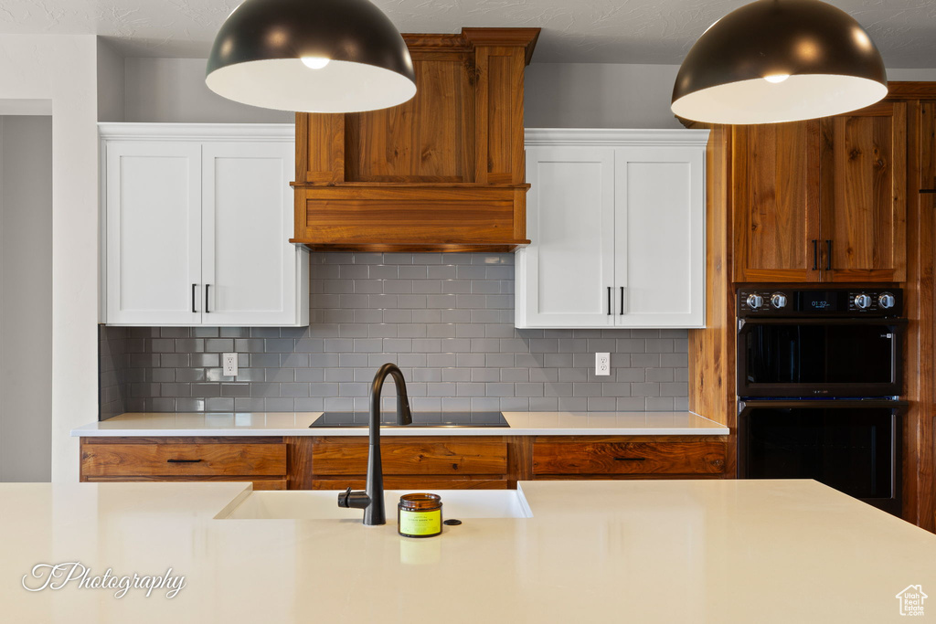 Kitchen with black appliances, light countertops, and white cabinets