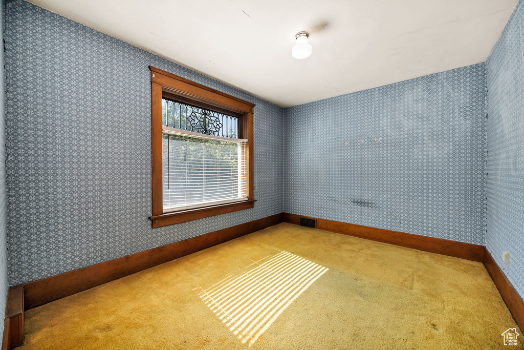 Carpeted empty room featuring wallpapered walls and baseboards
