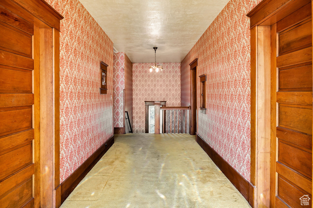 Hall featuring wallpapered walls, an upstairs landing, and a chandelier