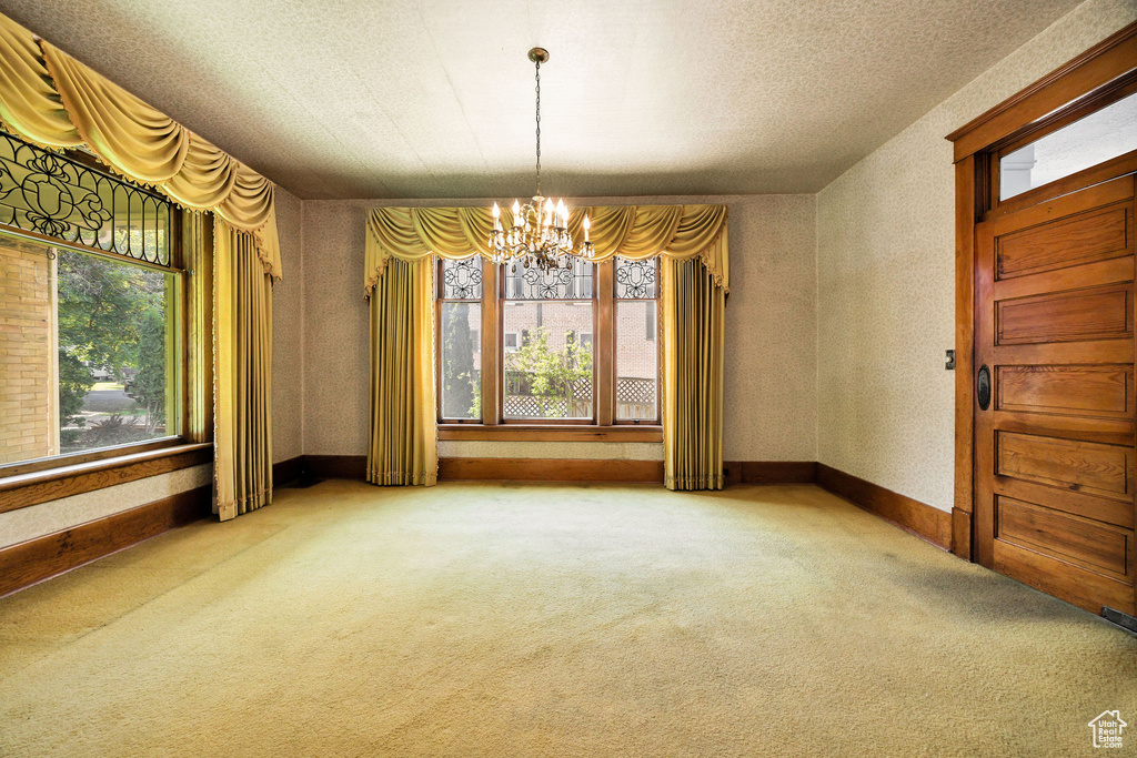 Unfurnished dining area featuring a chandelier, carpet floors, and baseboards