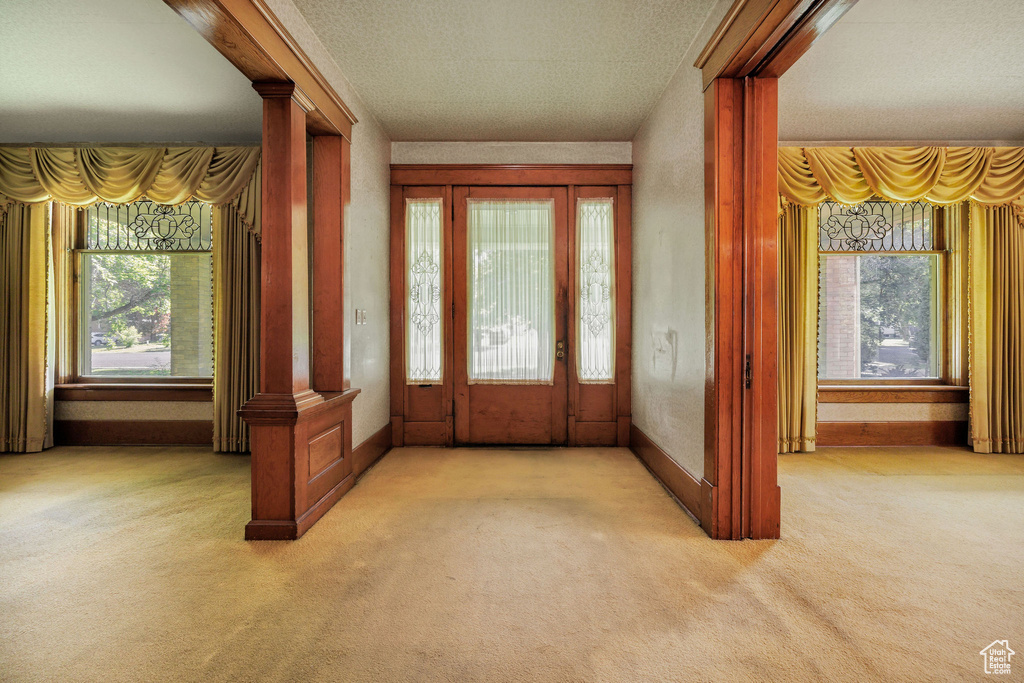 Carpeted entryway with baseboards and ornate columns