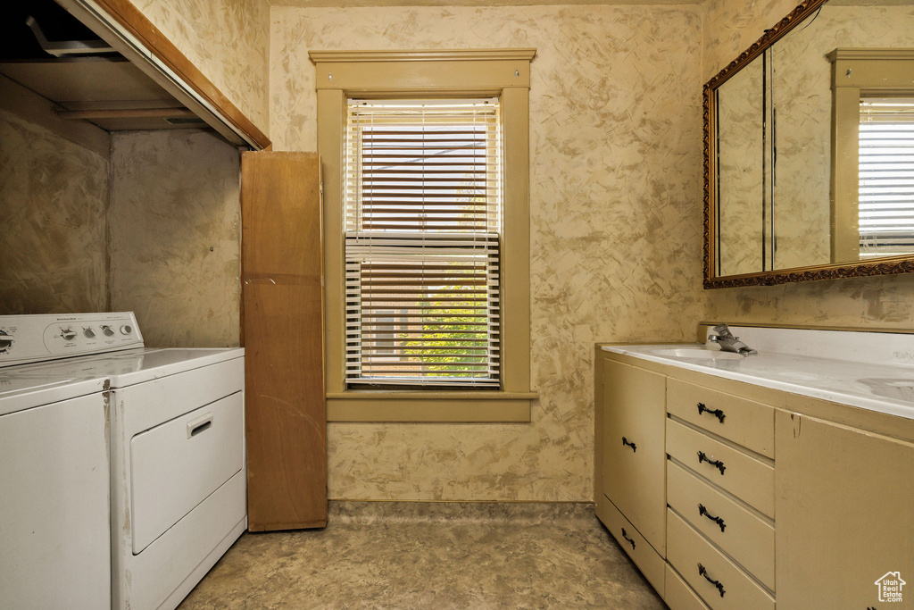 Laundry area with washing machine and dryer, a sink, and healthy amount of natural light