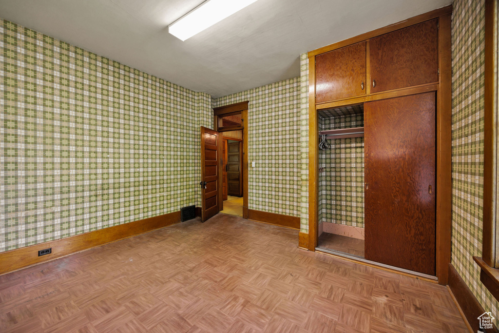 Unfurnished bedroom with baseboards, wallpapered walls, and a closet