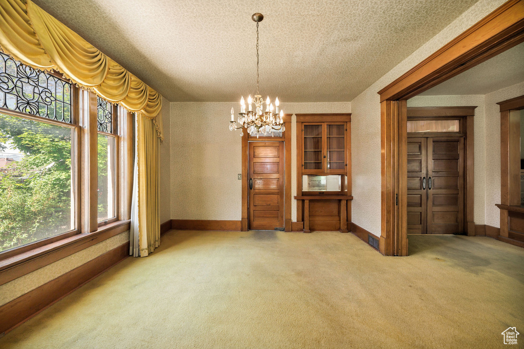 Dining space with light carpet, a chandelier, a textured ceiling, and baseboards