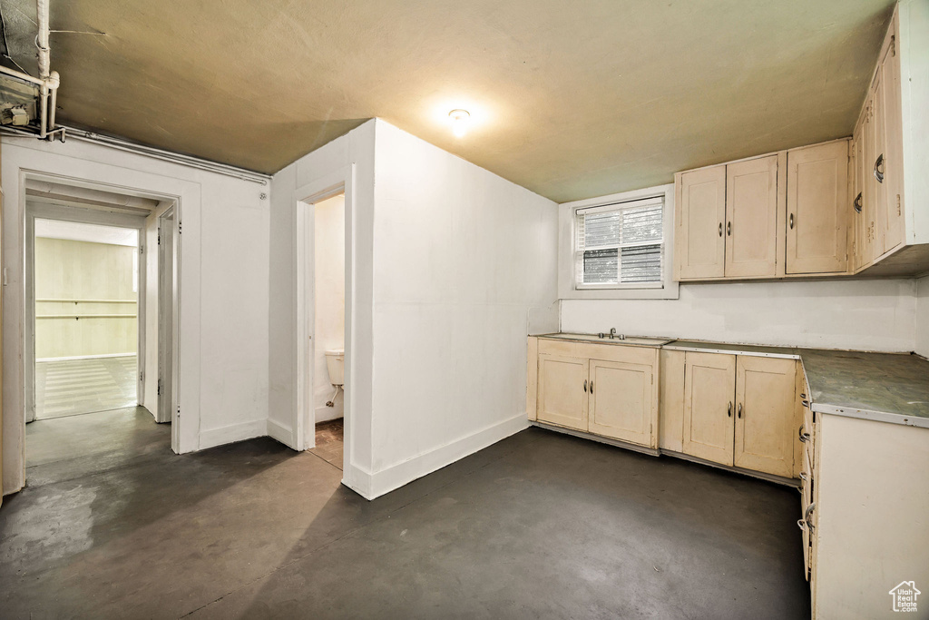 Kitchen featuring concrete flooring, baseboards, and a sink