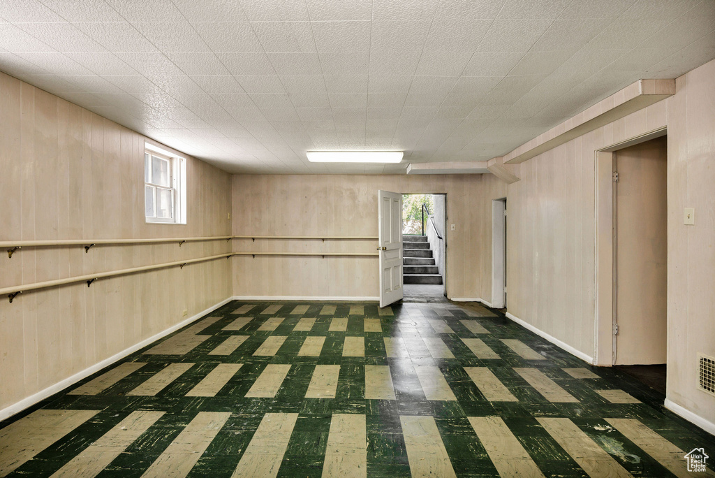 Basement featuring tile patterned floors, stairway, wooden walls, plenty of natural light, and baseboards