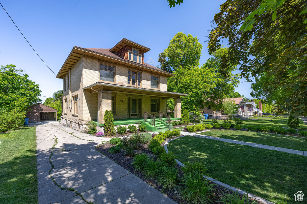 Traditional style home featuring a porch, brick siding, a front yard, an outdoor structure, and a detached garage